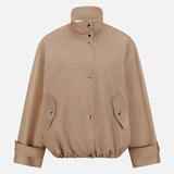 The ARLO MOTT Logan Tech Water Resistant Jacket is a light brown bomber crafted from smooth Italian gabardine with a slight sheen. It features a high collar, snap closure, flap pockets, elastic hem, and adjustable snap cuffs.