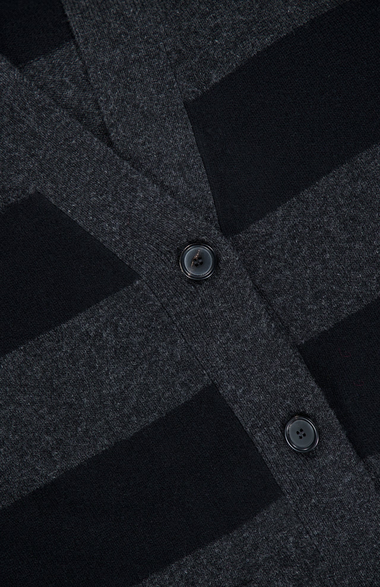 Close-up of the ARLO MOTT Lorimer Wool Cashmere Long Cardigan, showcasing its dark gray and black charcoal stripes and two black buttons. The fabric’s texture and button details are clearly visible, emphasizing the cozy feel of this oversized cardigan.