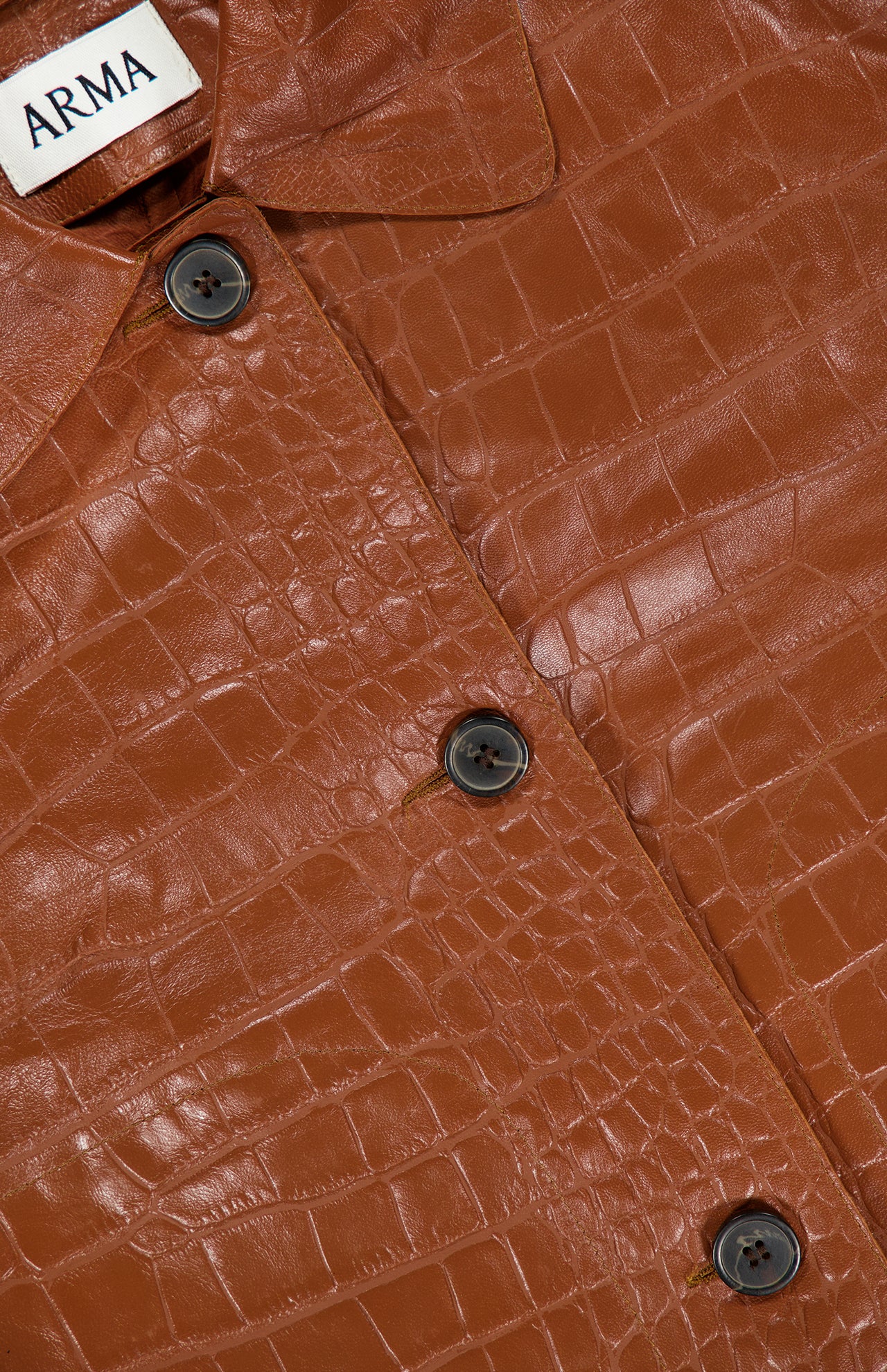 Close-up of the ARMA Emy Lamb Nappa Print Coat, featuring a brown crocodile-patterned leather design with black buttons and a visible ARMA label on the collar, highlighting the refined details of this tailored leather coat.