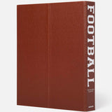 The ASSOULINE Football: The Impossible Collection is a large brown hardcover book with a textured football-like cover and bold white “FOOTBALL” on the spine—an ideal collector’s piece for college football or NFL history fans.