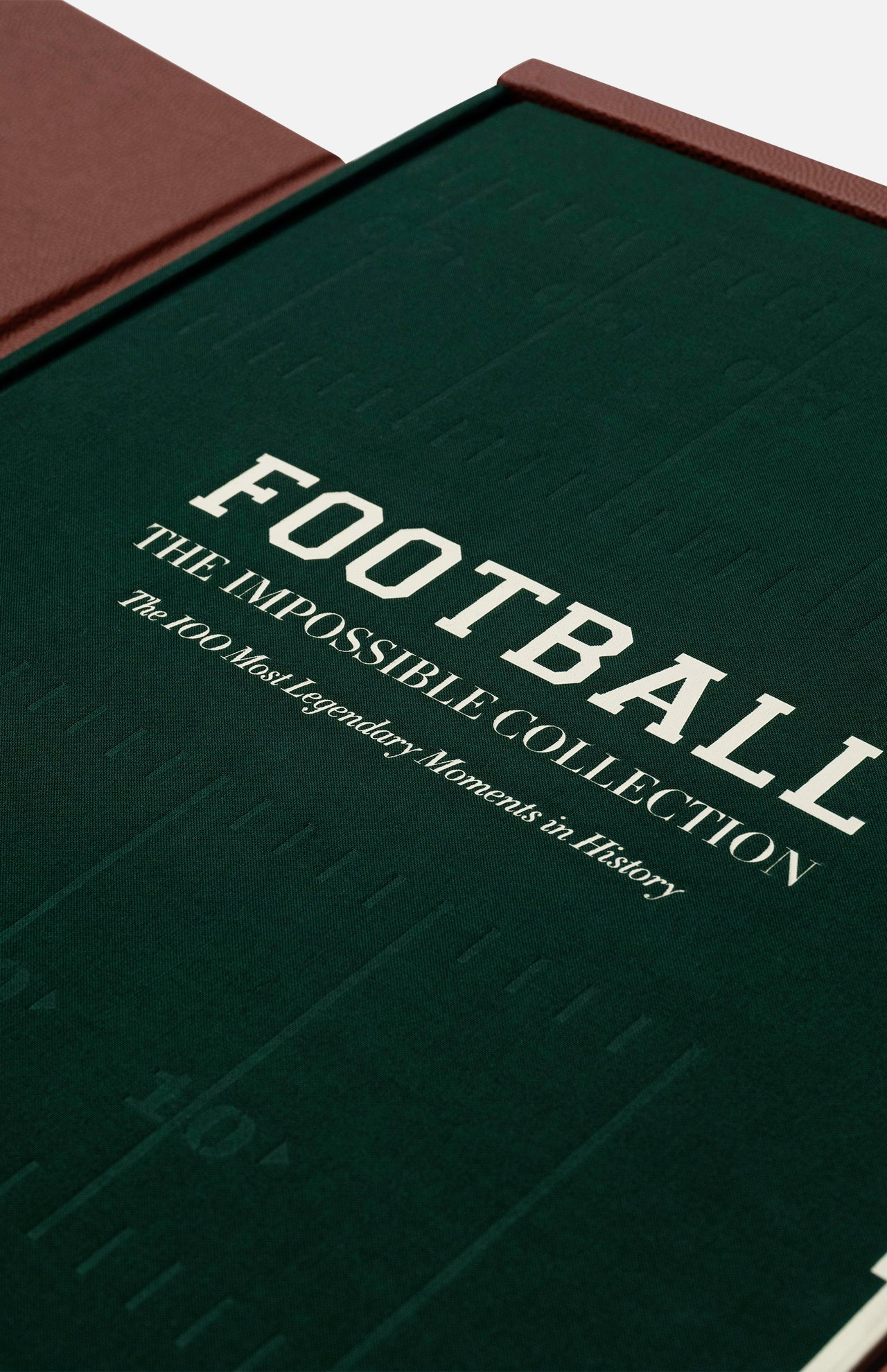 ASSOULINE’s "Football: The Impossible Collection" features a green cover with white text and subtle football field markings, highlighting 100 legendary moments in football. Presented inside an open brown slipcase.