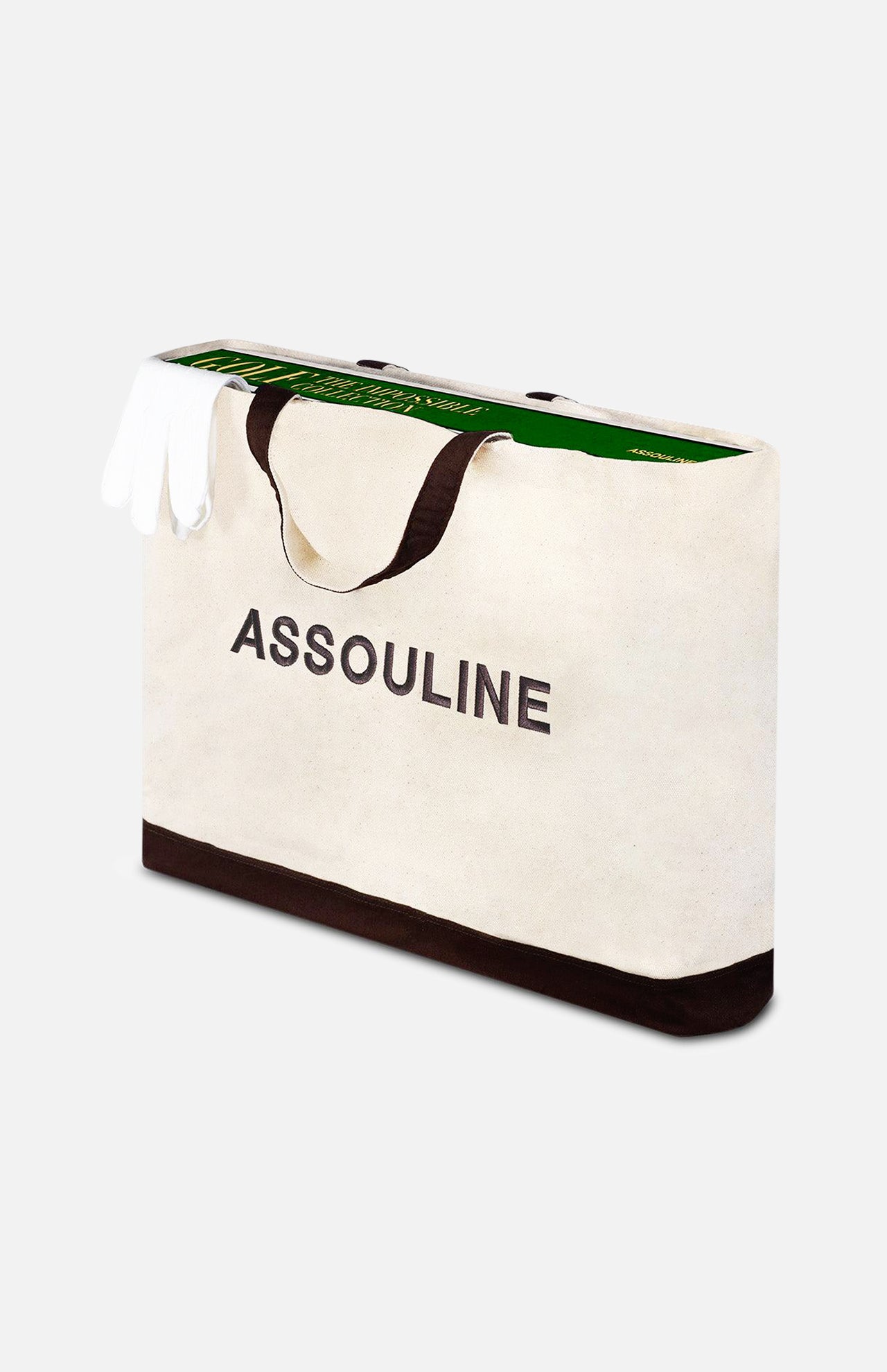 A large beige tote bag with black handles and ASSOULINE branding holds Golf: The Impossible Collection by ASSOULINE and a pair of white gloves peeking out.