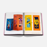 An open copy of "The Art of Tequila: Spirit of Mexico Book" by Assouline displays vibrant Mexican-inspired illustrations with blue, red, orange, and yellow backgrounds, featuring stylized human and animal figures.
