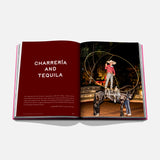 An open spread of Assouline’s "The Art of Tequila: Spirit of Mexico" shows “CHARRERÍA AND TEQUILA” on red and a nighttime photo of a charro performing rope tricks on horseback, celebrating tequila heritage and Mexican artistry.