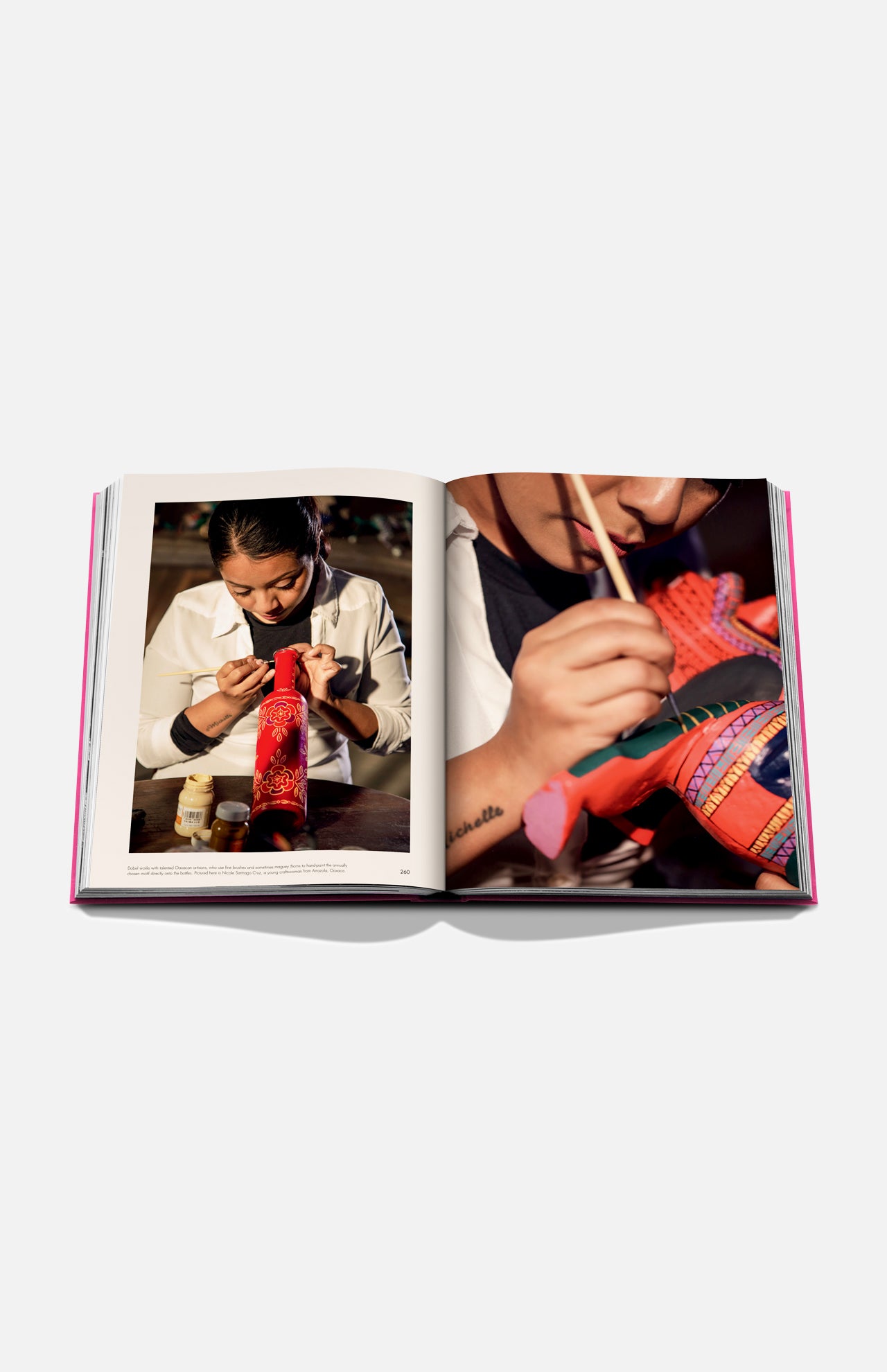 The Art of Tequila: Spirit of Mexico Book by Assouline showcases vibrant photos of Mexican art, including a person painting a decorative animal figurine. Art supplies and collectible tequila bottles are featured on the table.