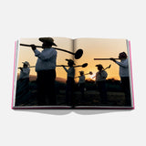 The Art of Tequila: Spirit of Mexico Book by Assouline features evocative images, such as people in hats with tools silhouetted at sunset, capturing tequila history and the essence of Mexican tradition and art.