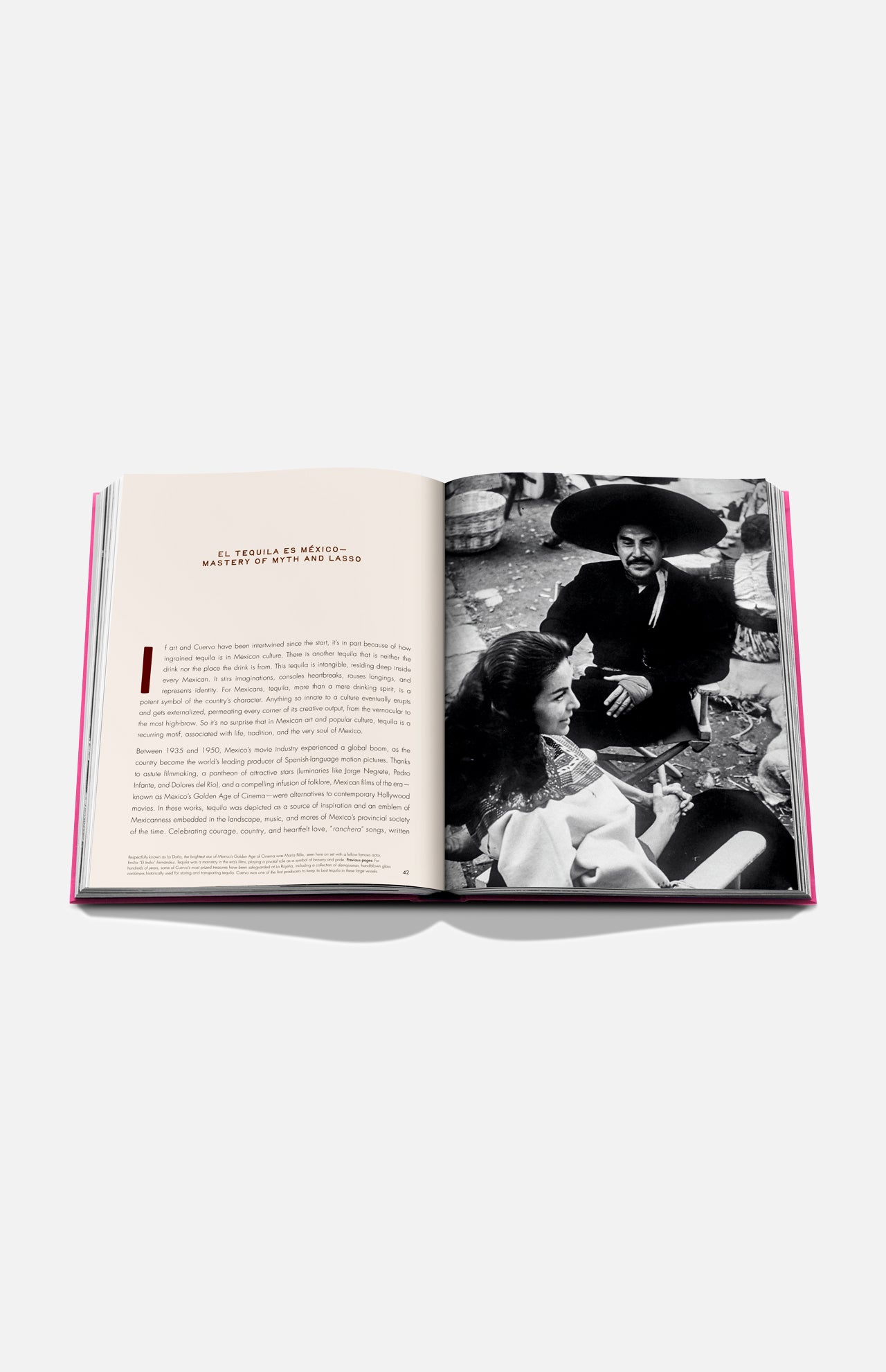 The Art of Tequila: Spirit of Mexico Book by Assouline shows an open page with text and a black-and-white photo of a smiling man in a sombrero with two women, reflecting tequila history and Mexican art.