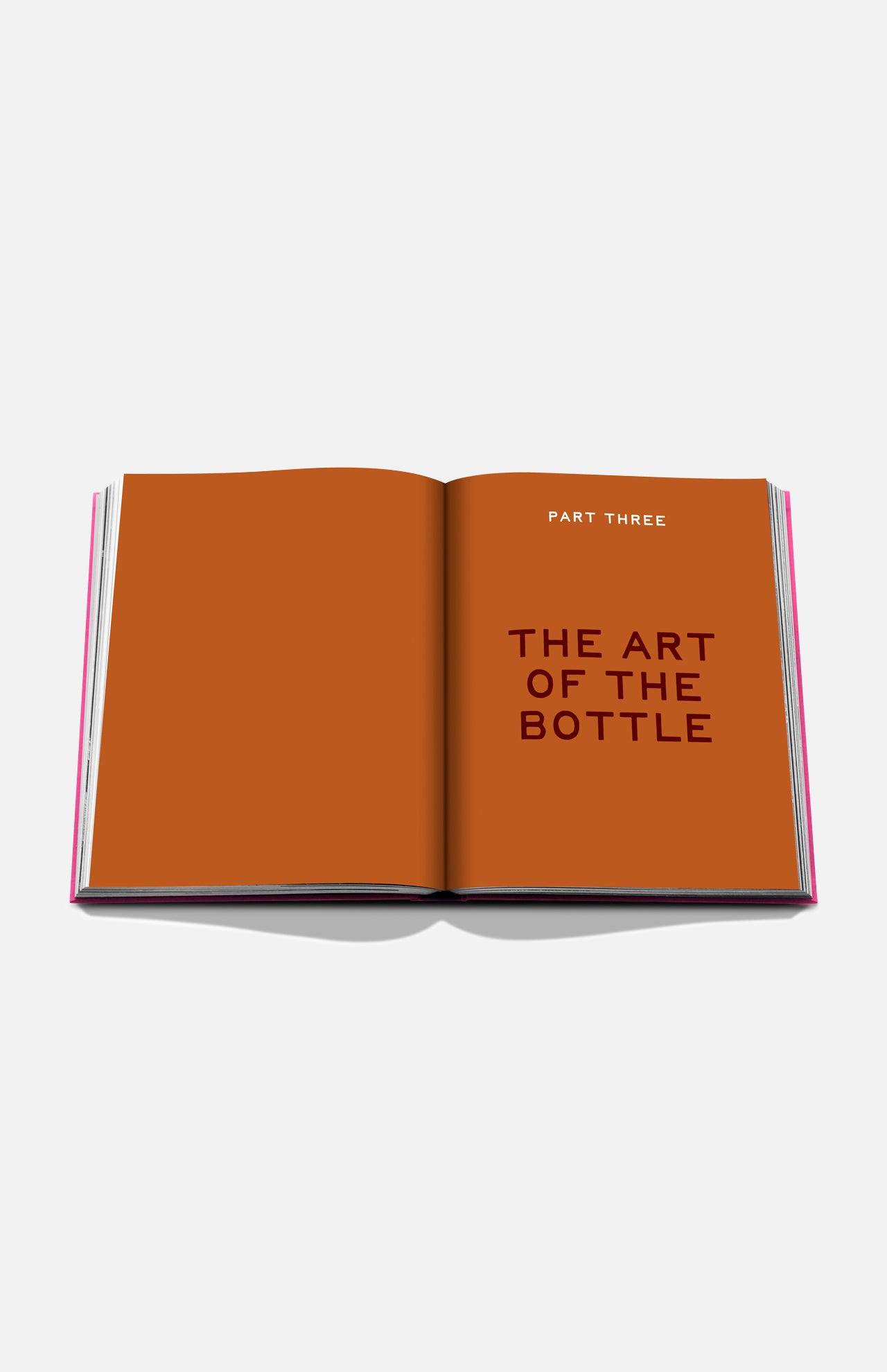 An open book titled "The Art of Tequila: Spirit of Mexico" by Assouline displays bold, dark text on orange pages, highlighting collectible tequila bottles and their relation to Mexican art.