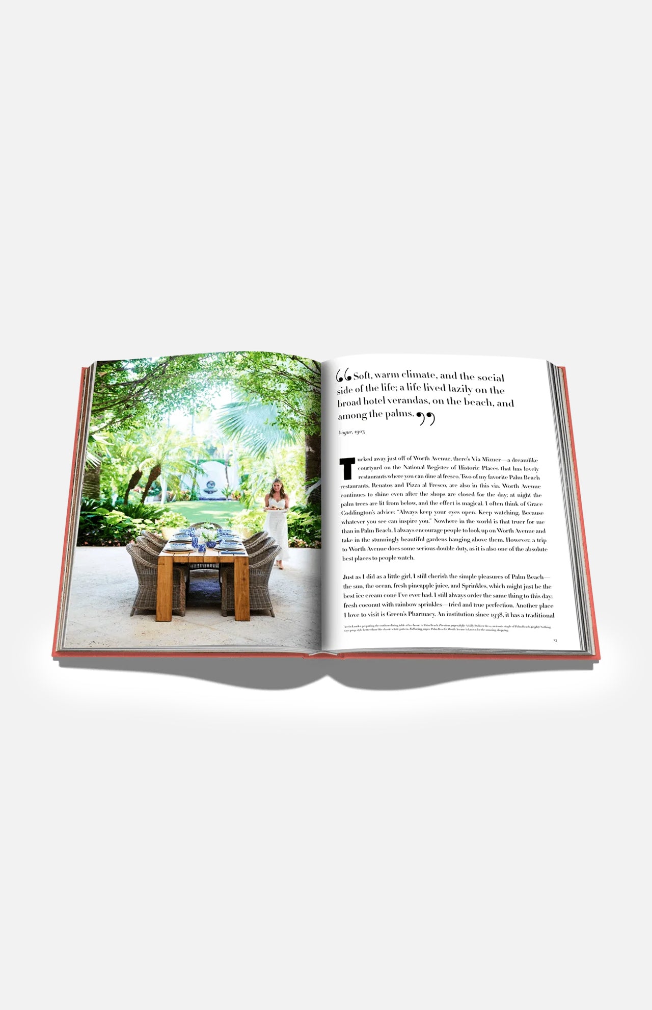 An open book from ASSOULINE titled “Palm Beach” displays a photograph of an outdoor dining table set amidst a lush garden, evoking the exclusive charm of Palm Beach. A woman stands nearby, while the opposite page features text with a prominent quote.