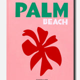 A pink book cover titled “Palm Beach” by ASSOULINE—featuring PALM in green, BEACH in light pink, a bold red flower illustration, and the brand name ASSOULINE in black at the bottom—captures the vibrant spirit of Palm Beach as an iconic luxury resort destination and exclusive community.