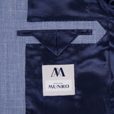 Close-up of the inside of the Melange Wool Silk and Linen Suit by ATELIER MUNRO, featuring a light blue lining, a pocket with a triangular flap, and a white label with the brand’s stylized AM logo.
