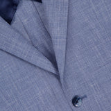Close-up of the ATELIER MUNRO Melange Wool Silk and Linen Suit jacket in light blue, showing its fine blend fabric, navy lining, part of the pocket, and a single dark button.