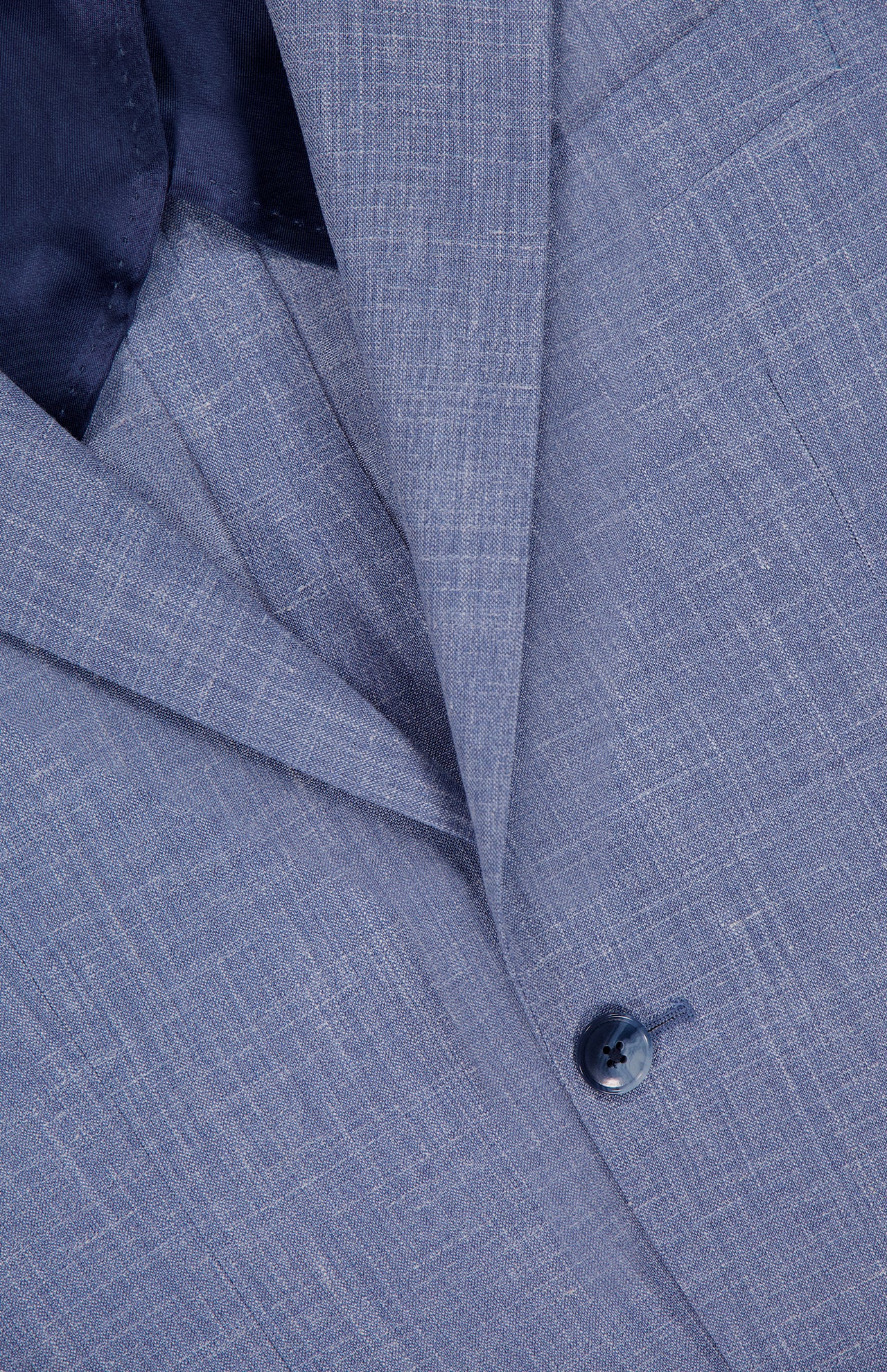Close-up of the ATELIER MUNRO Melange Wool Silk and Linen Suit jacket in light blue, showing its fine blend fabric, navy lining, part of the pocket, and a single dark button.