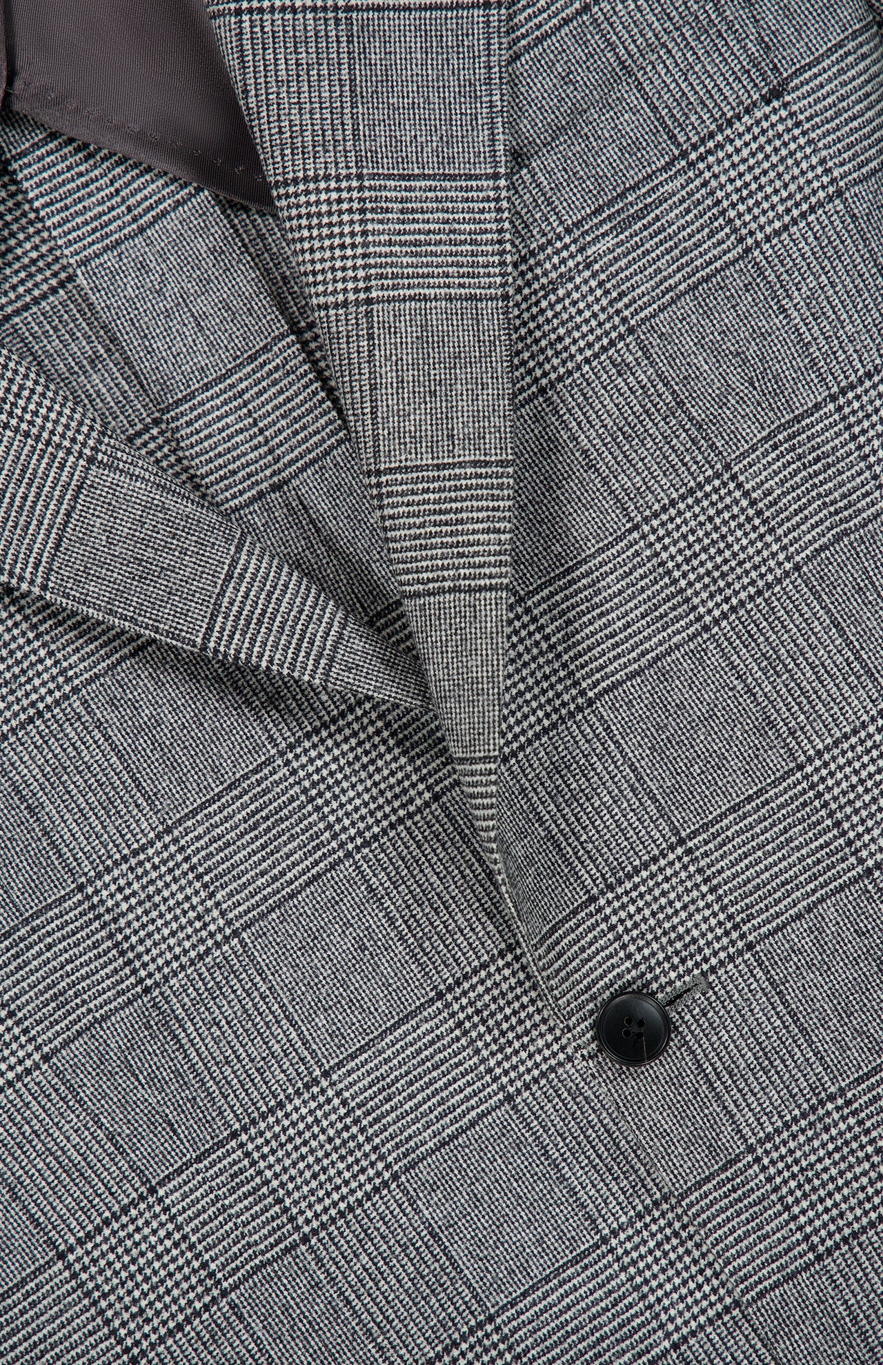 Close-up of the Peak Lapel Plaid Suit by ATELIER MUNRO, featuring black and white plaid fabric, a defined lapel, detailed stitching, and button—ideal for formal occasions or a timeless wool suit look.