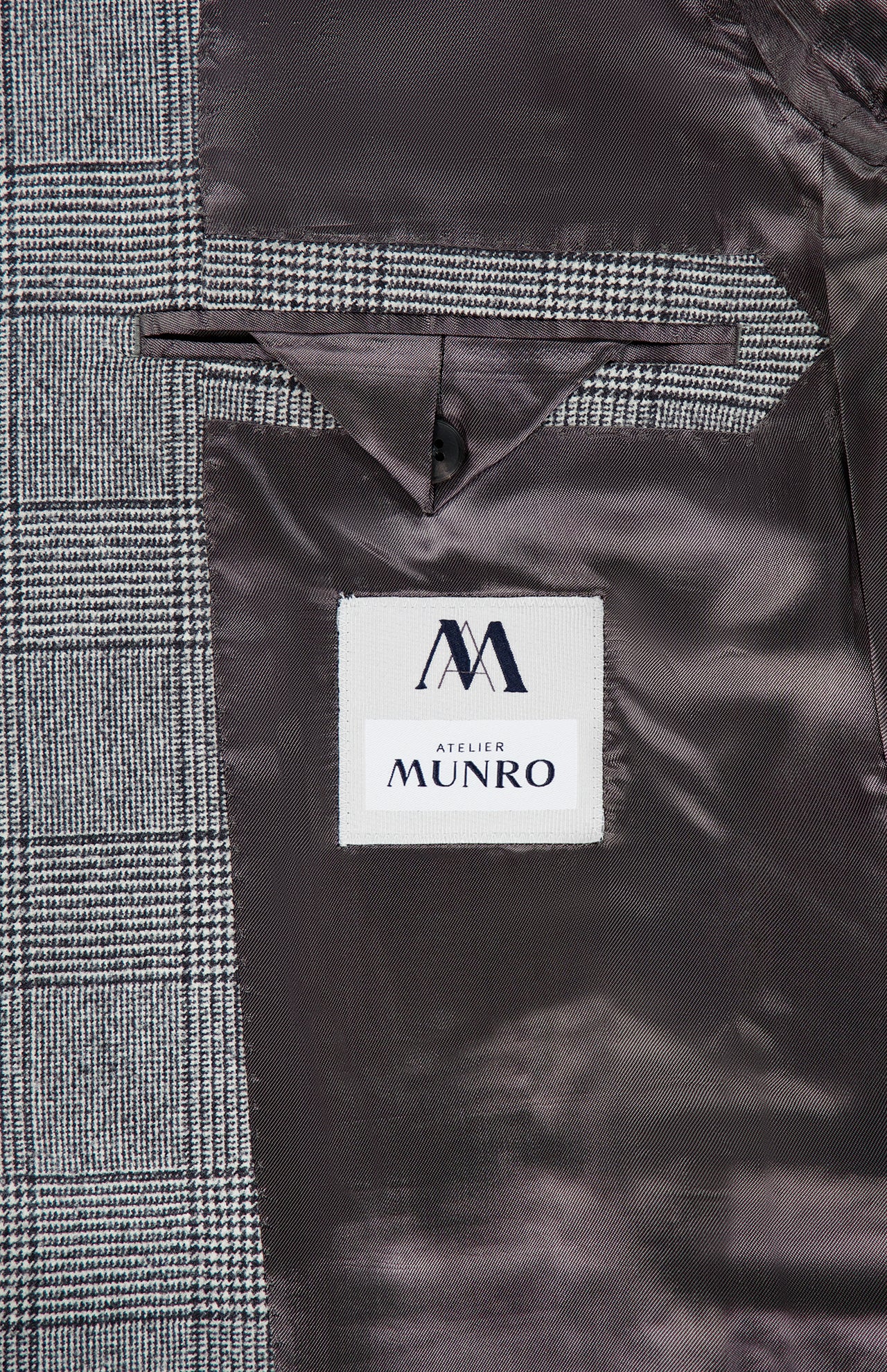 Close-up of the Peak Lapel Plaid Suit’s inner lining by ATELIER MUNRO, ideal for formal events, with a buttoned pocket and black-and-white plaid pattern paired with dark brown satin.