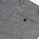 Close-up of the Peak Lapel Plaid Suit by ATELIER MUNRO, featuring gray checkered wool fabric, a black back pocket button, and belt loops—ideal for formal occasions.