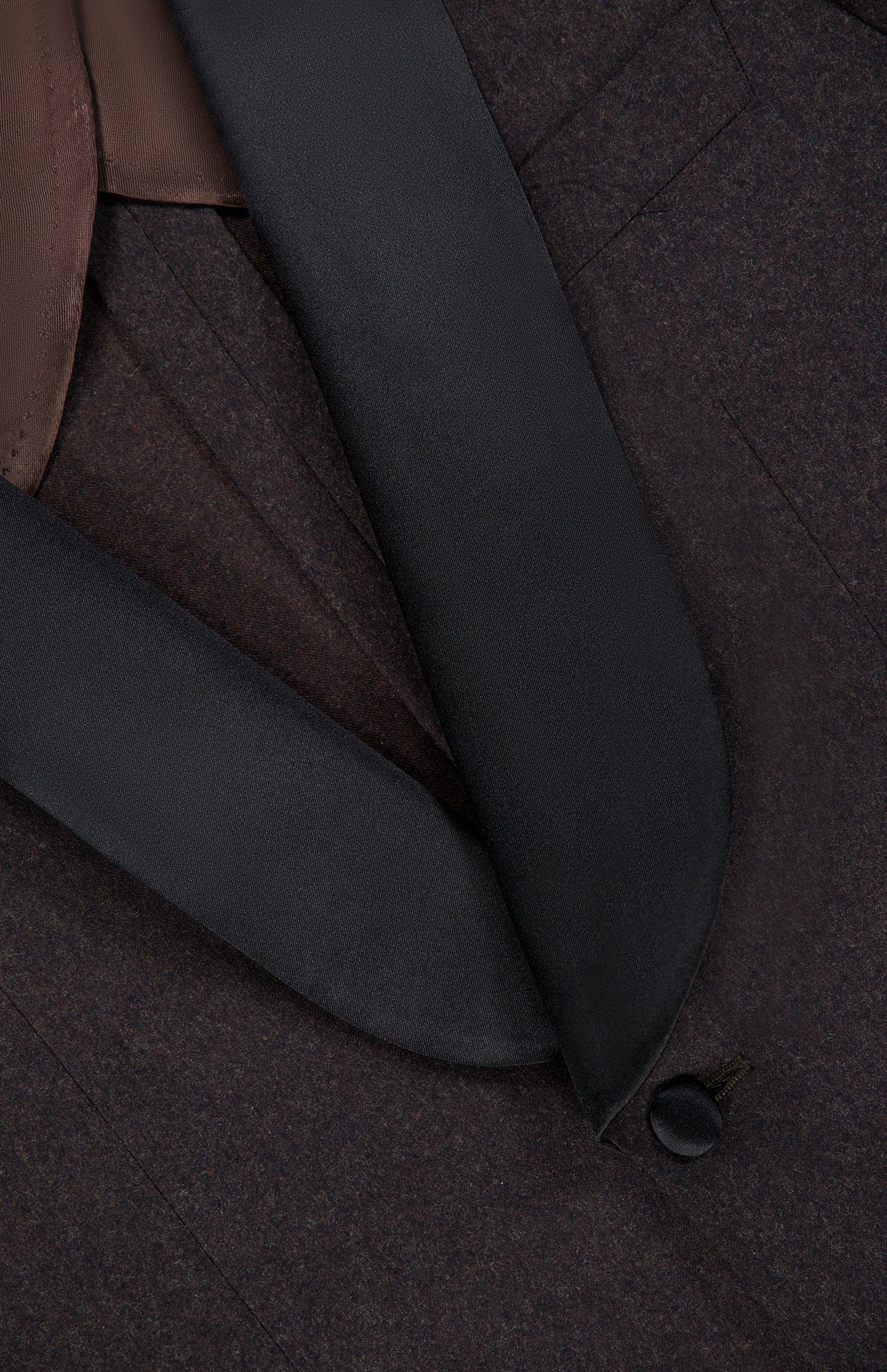 Close-up of the ATELIER MUNRO Shawl Lapel Tuxedo Suit featuring a pure wool jacket with black satin shawl lapel, brown inner lining, fine stitching, and a fabric-covered button.