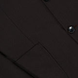 Close-up of the ATELIER MUNRO Wide Notch Lapel Solid Suit in dark brown, highlighting the pocket, lapel, and two black buttons.