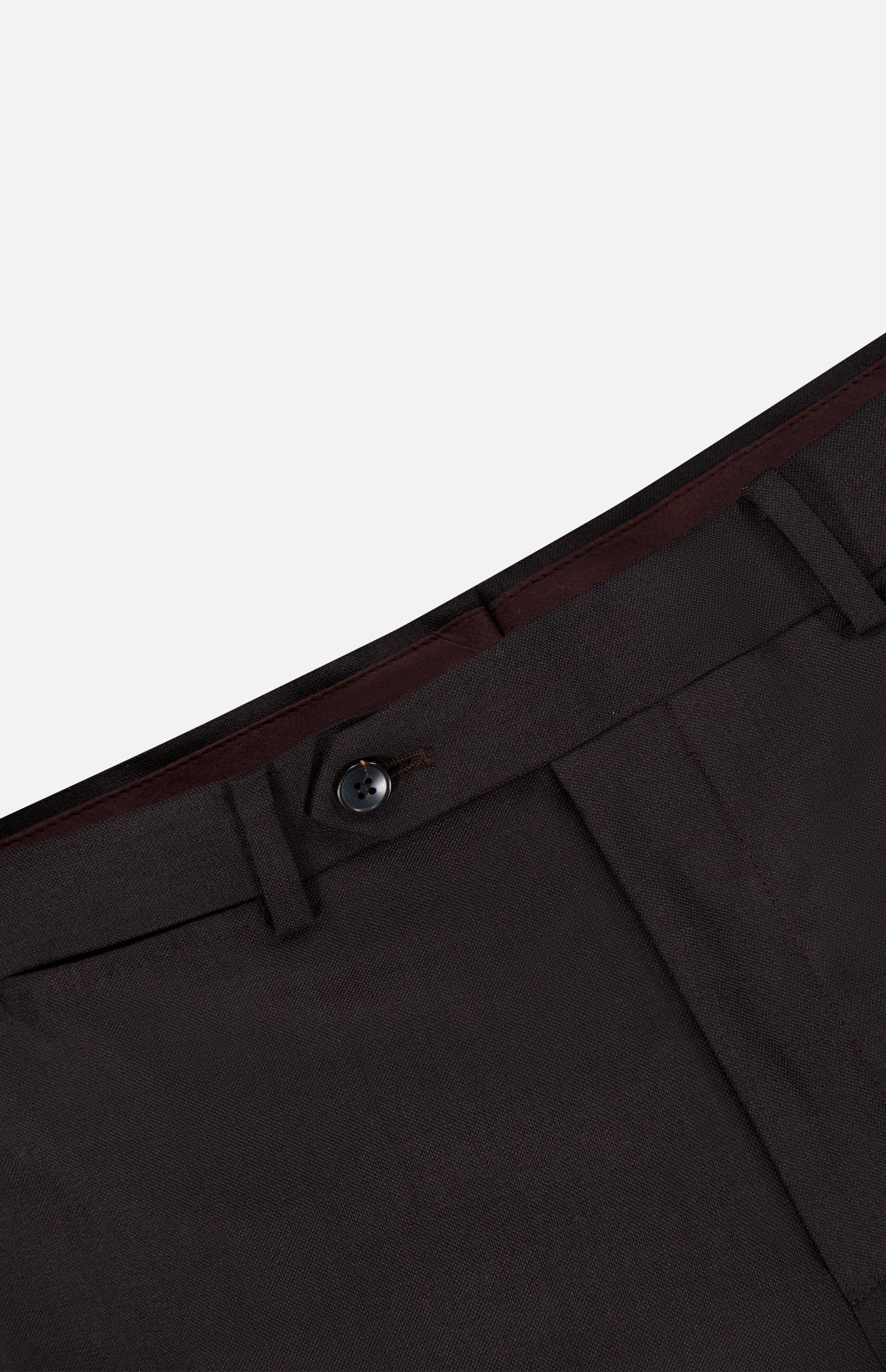 Close-up of the waistband and upper section of the Wide Notch Lapel Solid Suit by ATELIER MUNRO, featuring a black button, belt loops, front pocket seam, and burgundy lining on this wool blend suit.