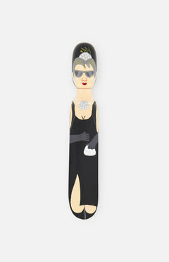 WEDGIE’s ‘Auds’ Wood Door Stopper features a hand-painted woman in a black dress, gloves, sunglasses, pearls, and tiara—an eye-catching piece inspired by Breakfast at Tiffany’s.