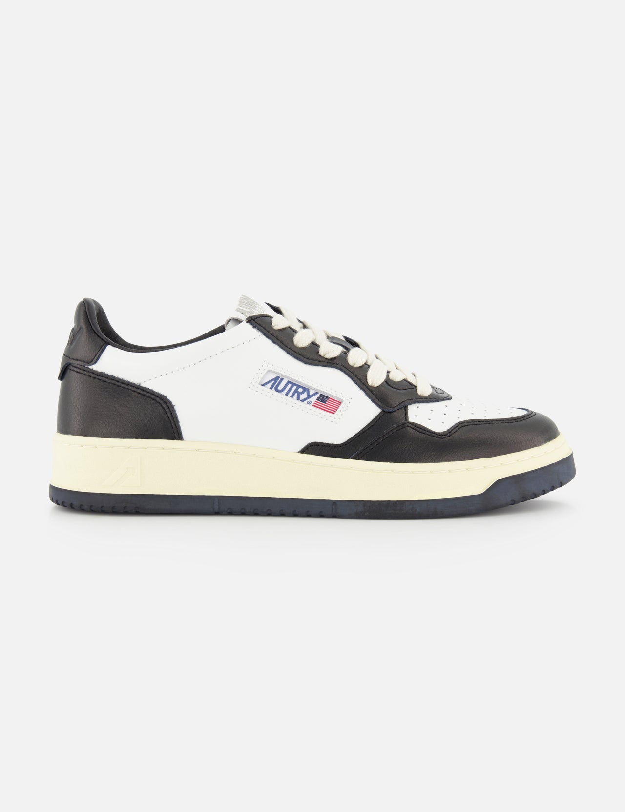The AUTRY Medalist Low Bicolor Sneakers are black and white low-tops inspired by 1980s tennis shoes, with a cream sole, Autry branding, and a small American flag on the side.