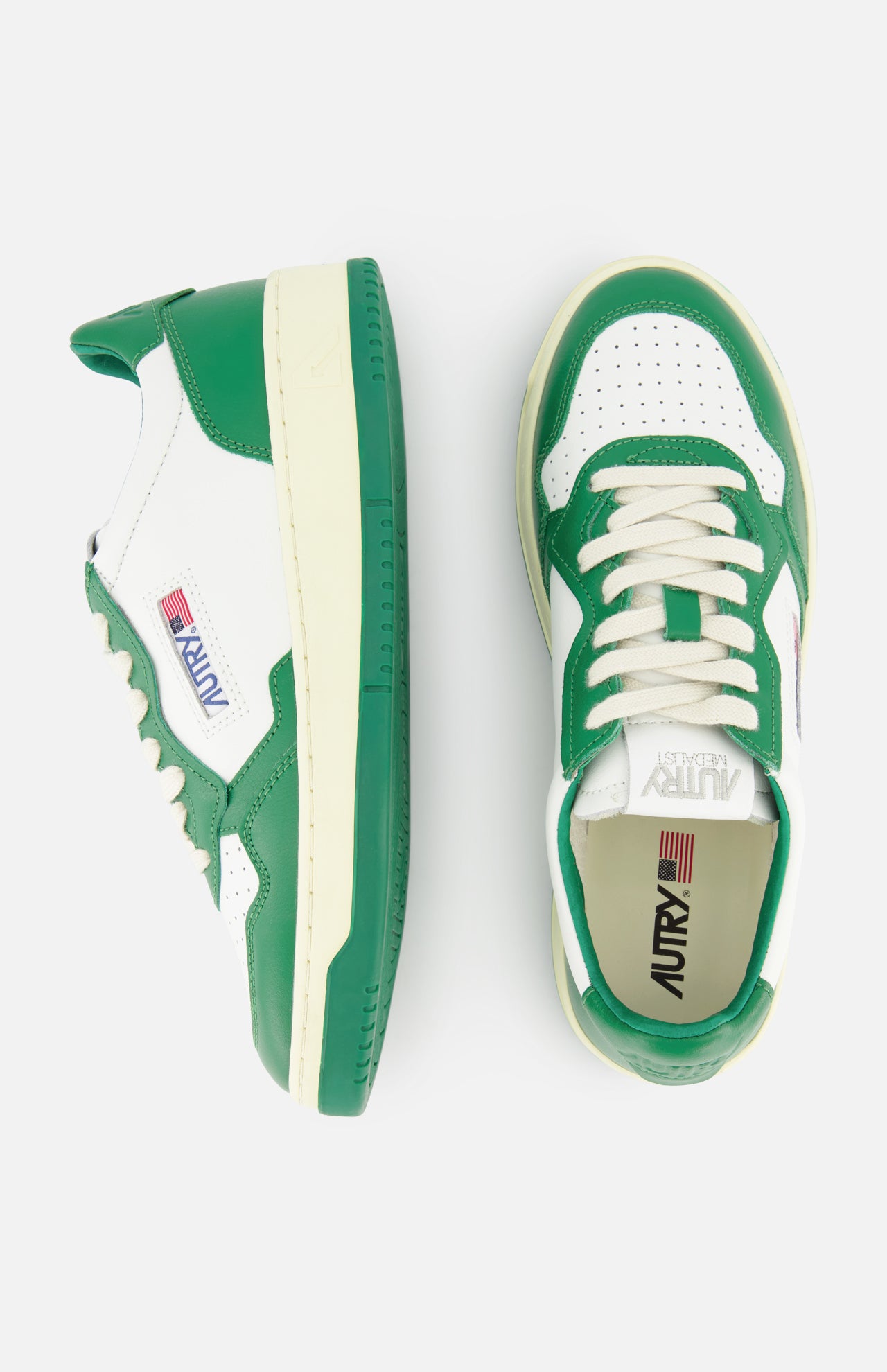 The AUTRY Medalist Low Bicolor Sneakers feature green and white panels, cream laces, the signature AUTRY logo, and an American flag patch on the side—perfect as stylish white tennis shoes. One shoe is shown from the side, the other from above.