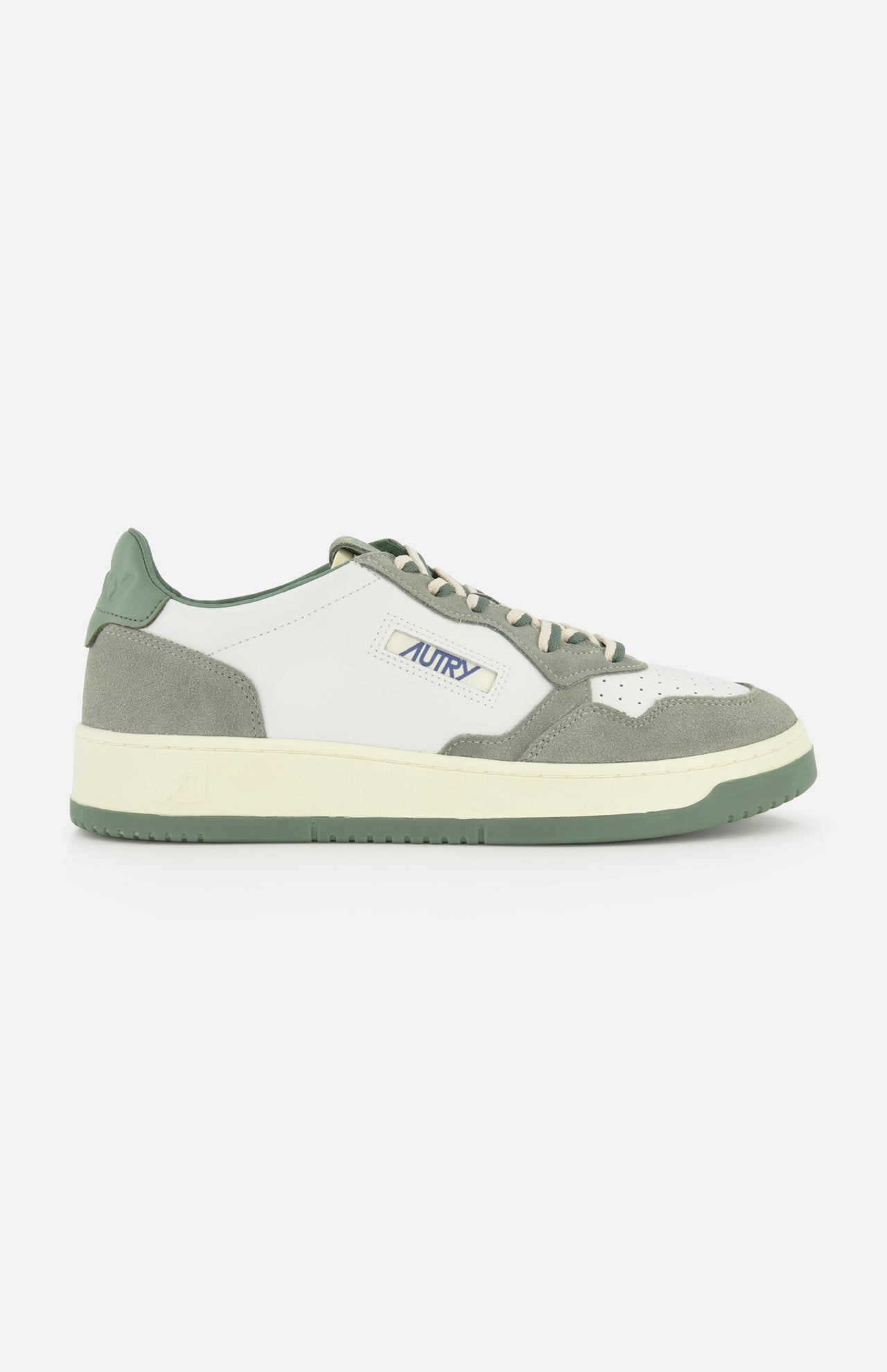 The AUTRY Medalist Low Leather Suede Sneaker features a white and gray design with green accents, cream laces, and a green sole. Inspired by 1980s tennis shoes, it sports the AUTRY logo and an American flag on the side for a classic retro look.