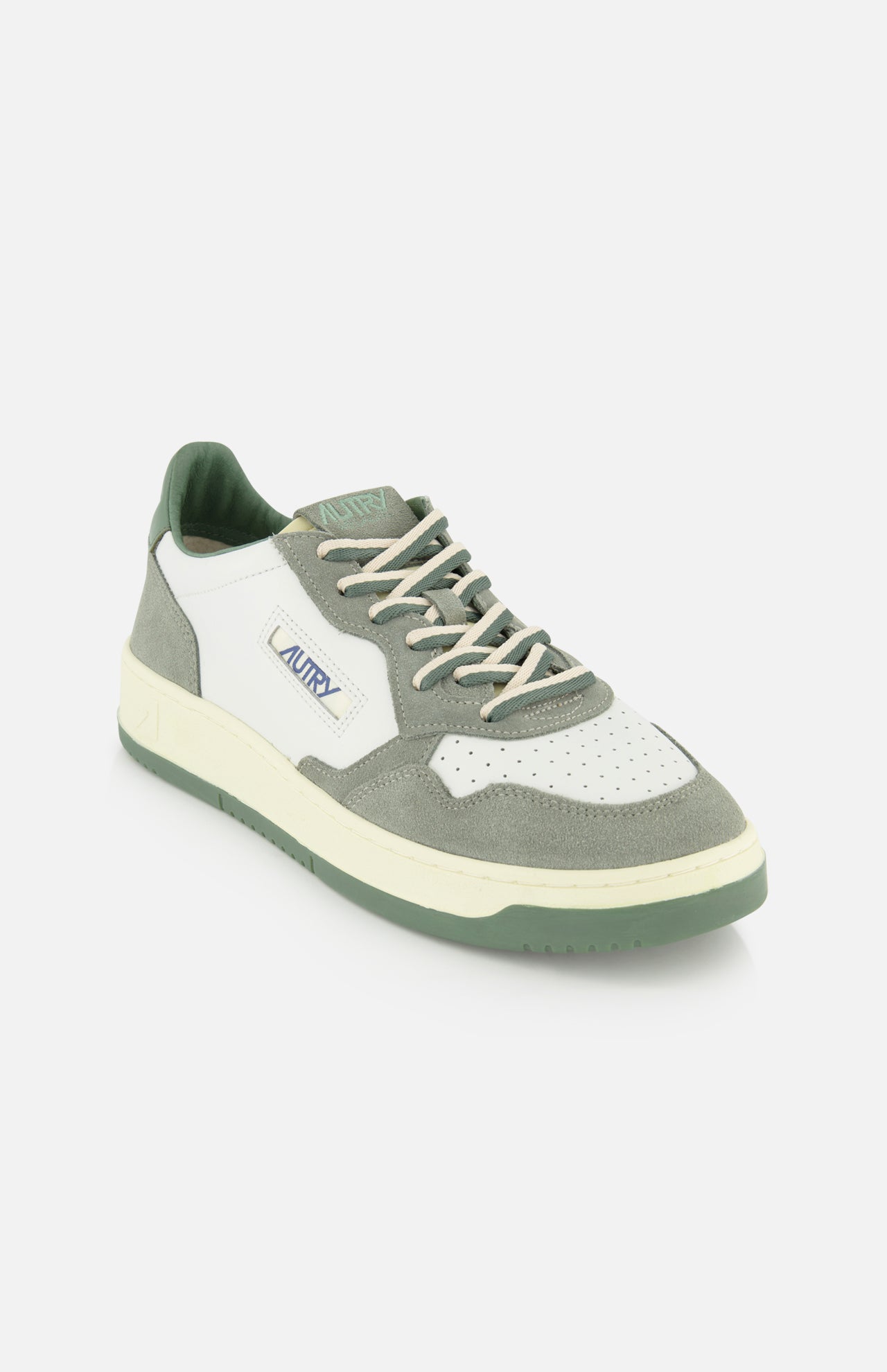 The AUTRY Medalist Low Leather Suede Sneaker features a white leather upper with perforated toe, light gray and green suede panels, green platform sole, white laces, and classic 1980s-inspired AUTRY branding on the side and tongue.
