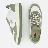 The AUTRY Medalist Low Leather Suede Sneaker in white and sage green features suede and leather panels, perforated toe area, cream laces, and a green rubber sole—styles inspired by 1980s tennis shoes, shown from side and top views.