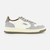 The AUTRY Medalist Low Man Leather Suede Sneaker is a white and gray low-top inspired by 1980s tennis shoes, crafted with suede and leather panels, gray laces, and the signature Autry logo on the side. The sneaker is finished with a cream sole, brown heel tab, and classic retro styling throughout.