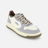 Introducing the AUTRY Medalist Low Man Leather Suede Sneaker—a white leather sneaker inspired by classic 1980s tennis shoes. This design features light gray and beige accents, perforated toe detailing, soft gray suede overlays, and the signature AUTRY logo on the side. The look is completed with a cream-toned platform sole and light brown laces for an authentic vintage aesthetic.