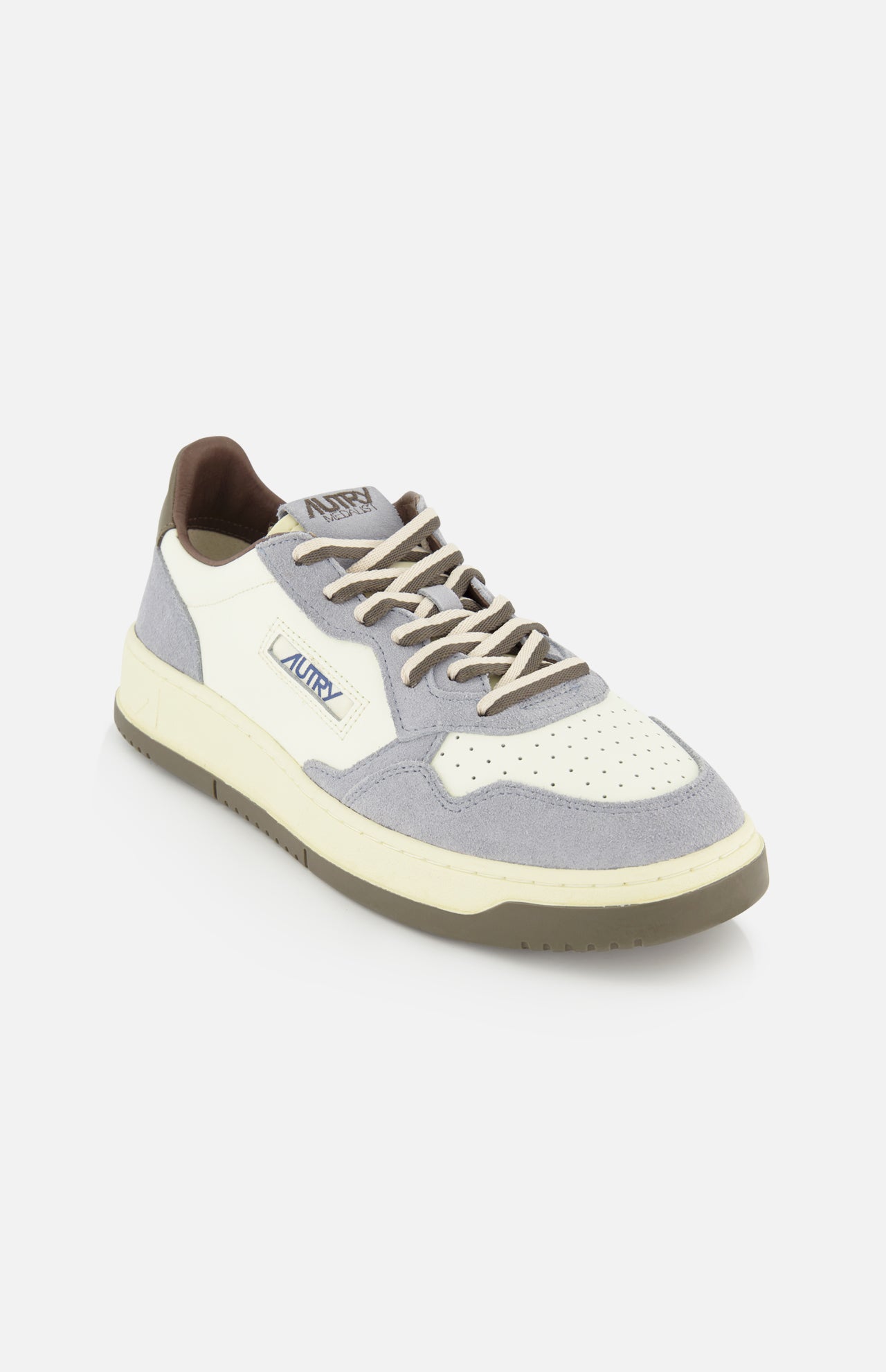 Introducing the AUTRY Medalist Low Man Leather Suede Sneaker—a white leather sneaker inspired by classic 1980s tennis shoes. This design features light gray and beige accents, perforated toe detailing, soft gray suede overlays, and the signature AUTRY logo on the side. The look is completed with a cream-toned platform sole and light brown laces for an authentic vintage aesthetic.