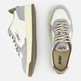 The AUTRY Medalist Low Man Leather Suede Sneaker, shown in cream and gray with brown accents, is crafted from white leather and features a subtle platform sole inspired by classic 1980s tennis shoe design. Presented in both side and top views against a white background.