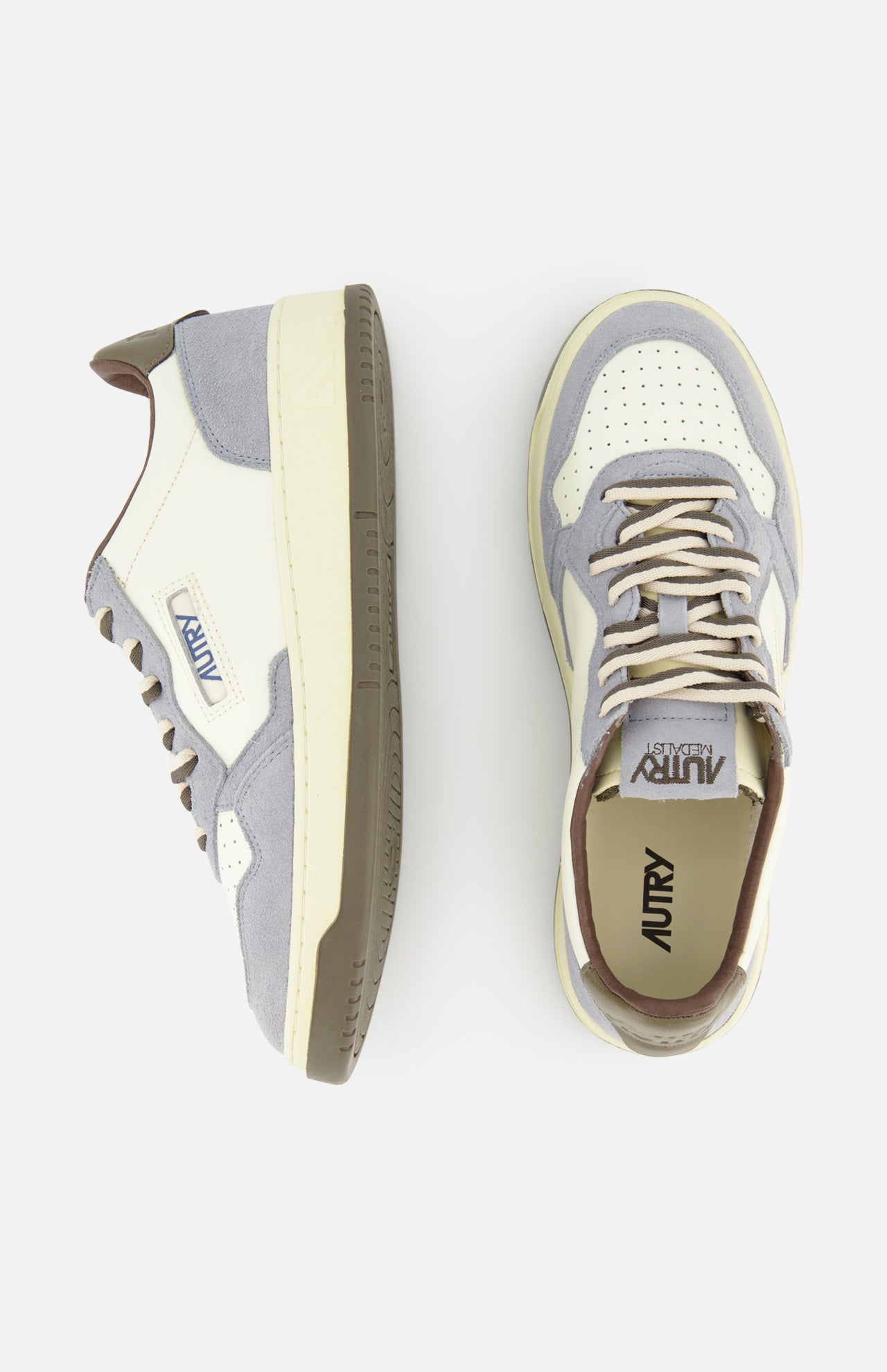 The AUTRY Medalist Low Man Leather Suede Sneaker, shown in cream and gray with brown accents, is crafted from white leather and features a subtle platform sole inspired by classic 1980s tennis shoe design. Presented in both side and top views against a white background.