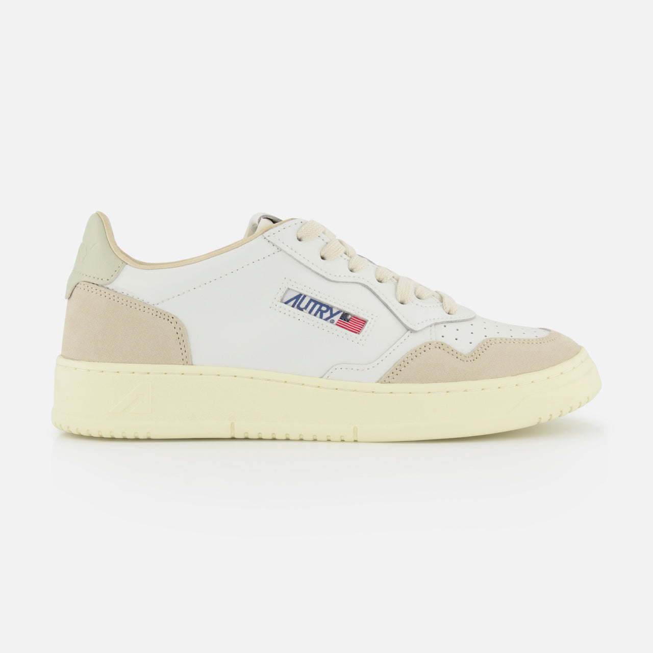 The AUTRY Medalist Low Man Leather Suede Sneaker is a white low-top inspired by 1980s tennis shoes, featuring beige accents, suede details on the toe and heel, a cream sole, white laces, and the “Autry” logo with an American flag.