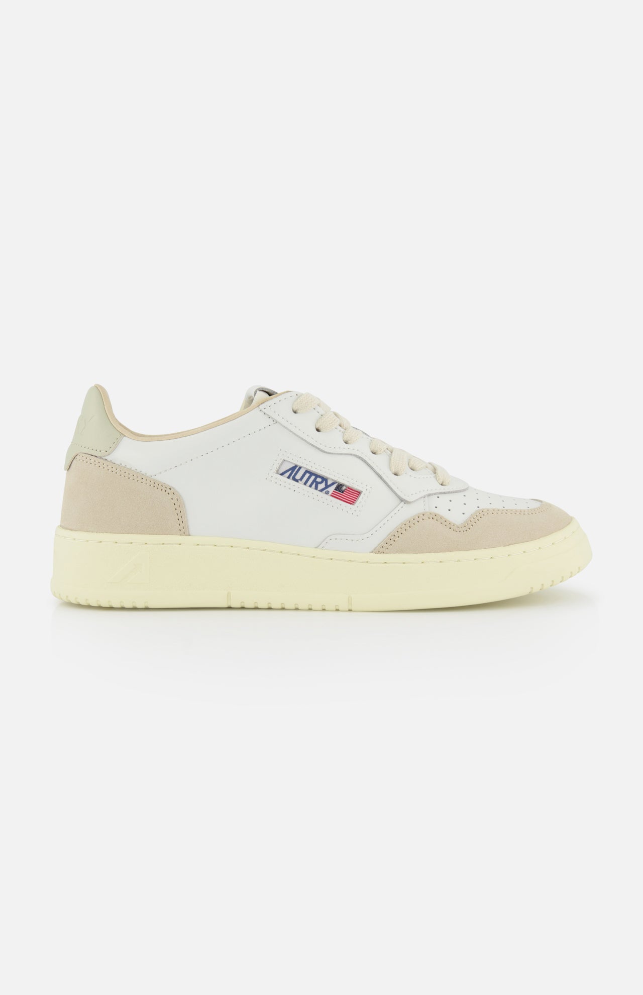 The AUTRY Medalist Low Man Leather Suede Sneaker is a white low-top inspired by 1980s tennis shoes, featuring beige accents, suede details on the toe and heel, a cream sole, white laces, and the “Autry” logo with an American flag.
