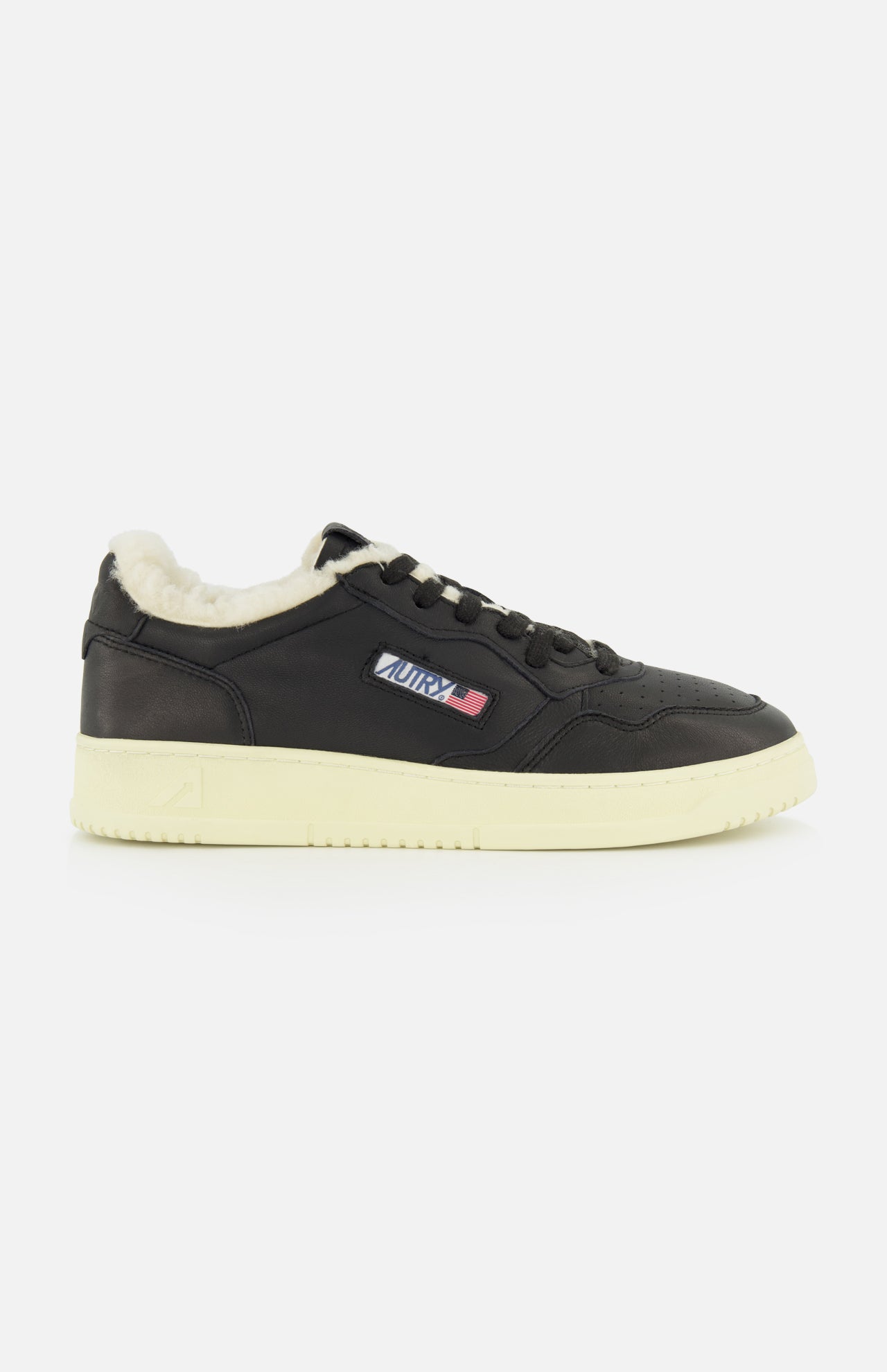 The Medalist Low Man Shearling Sneaker by AUTRY is a black low-top leather sneaker featuring a cream platform sole, plush shearling lining, and a small AURA logo patch with red, white, and blue stripes on the side. The shoe is shown against a plain white background.