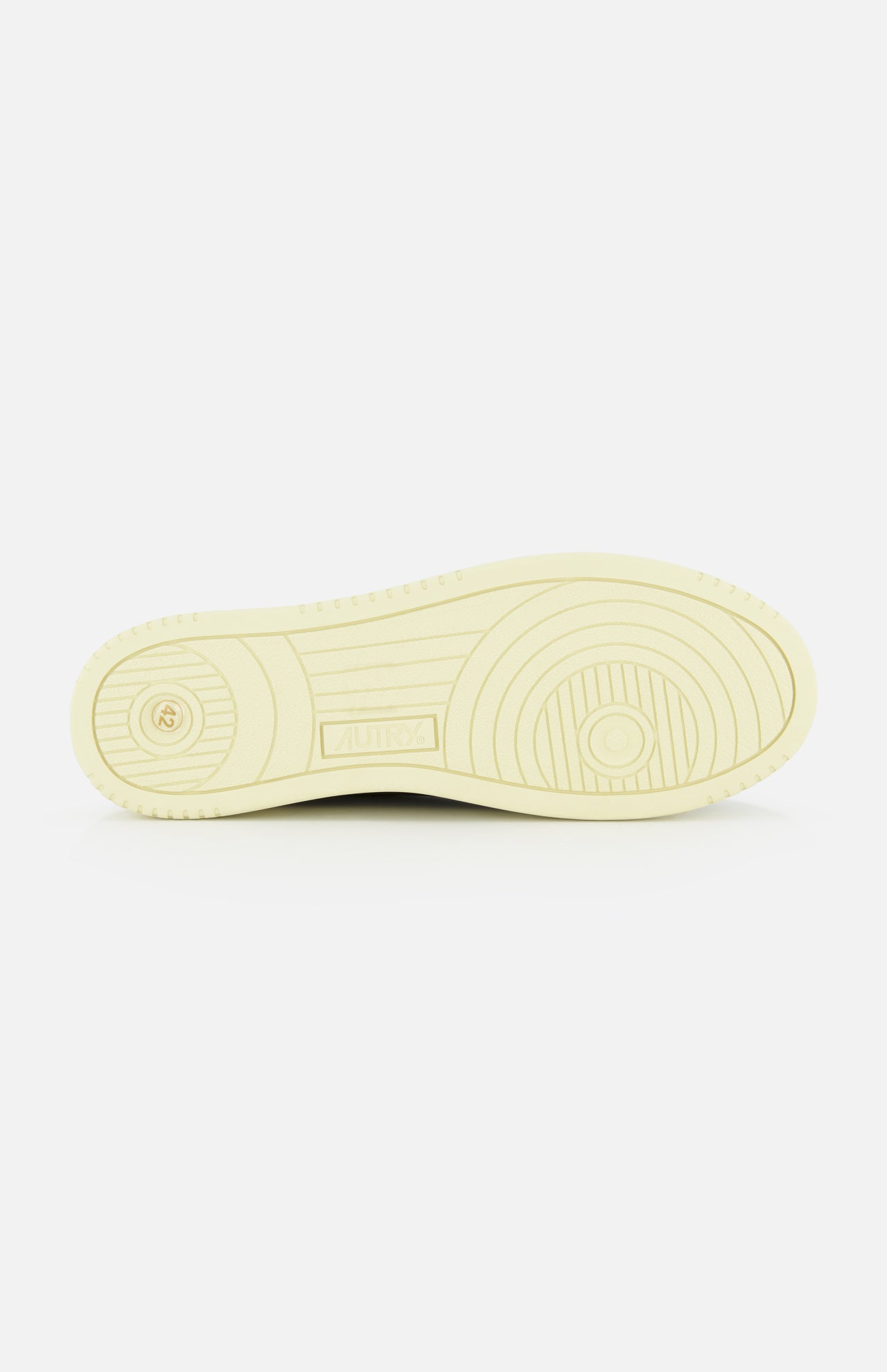 The image displays the bottom view of a single AUTRY Medalist Low Man Shearling Sneaker in beige, highlighting its circular and straight tread patterns on a platform sole, set against a white background.