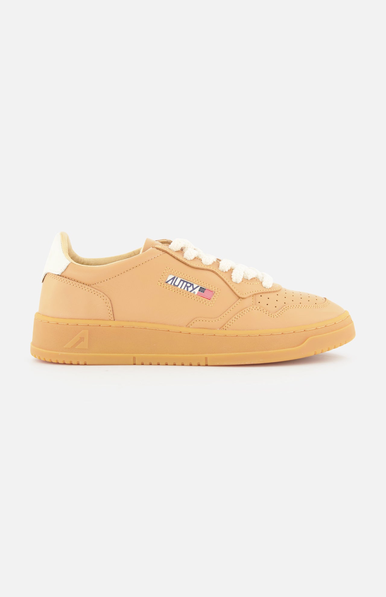 The AUTRY Medalist Low Man Sneaker features tan leather, a light brown sole, white knit laces, an embroidered American flag and "AUTRY" patch on the side, and a white heel, shown in profile against a white background.