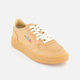 The AUTRY Medalist Low Man Sneaker features a tan leather upper, white knit laces, a gum rubber sole, and a small rectangular side patch displaying the AUTRY brand name and American flag. Photographed on a white background.