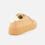 The AUTRY Medalist Low Man Sneaker with Knit Laces is a tan low-top shoe with a white heel tab, beige knit laces, a small rectangular side logo, and a platform sole, shown from a rear side angle on a white background.