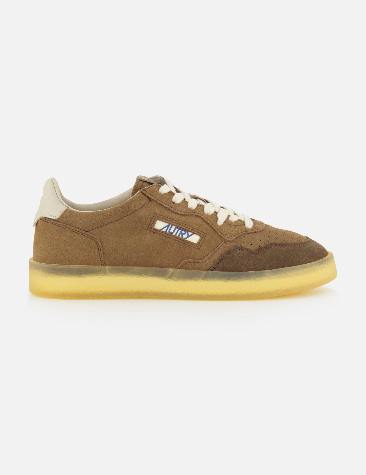 The Medalist Low Man Suede Leather Sneaker by AUTRY features brown suede uppers, a beige sole, cream laces, and a distinctive small side cutout that reveals patterned fabric beneath. Inspired by vintage tennis shoes, this low-top sneaker is showcased against a plain white background.