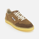 Introducing the AUTRY Medalist Low Man Suede Leather Sneaker—a classic brown suede low-top inspired by vintage tennis shoes. This stylish sneaker features white laces, a beige interior, and a translucent yellow sole. The side is adorned with the signature AUTRY logo patch and an American flag for an authentic touch. Angled slightly to the left, the shoe is showcased against a plain white background.