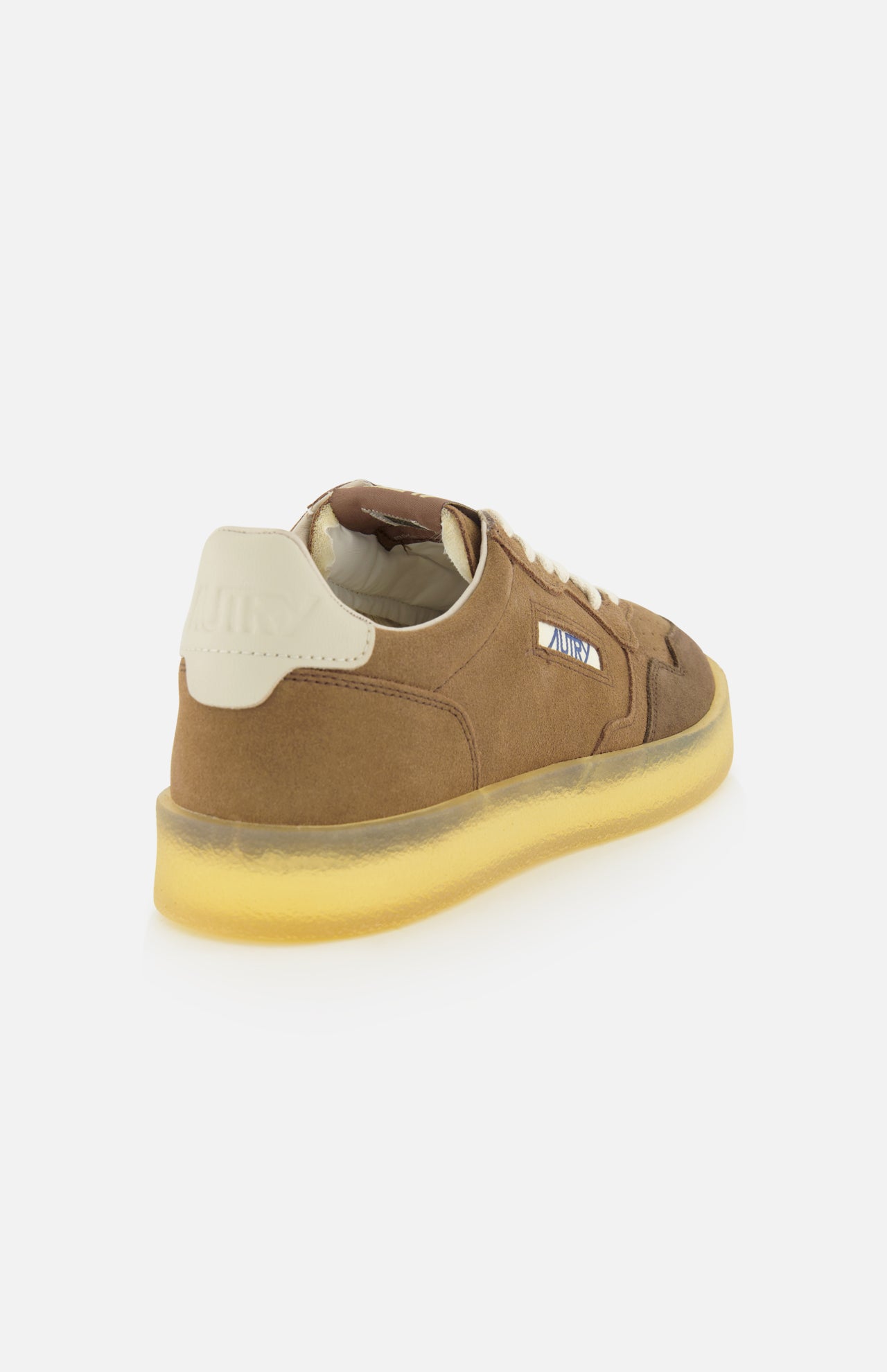 The AUTRY Medalist Low Man Suede Leather Sneaker, featuring a brown suede upper, white laces, a white heel tab, and a translucent yellow sole, is displayed at an angle on a white background.