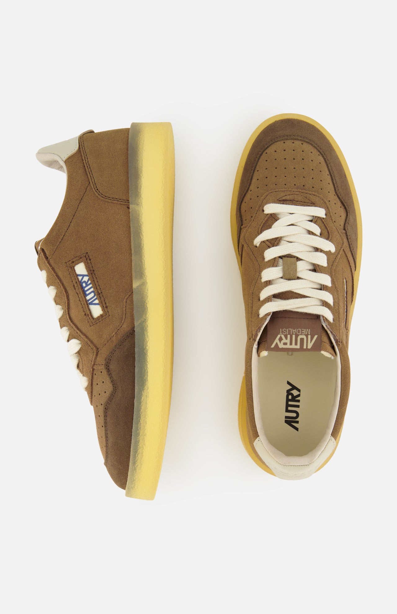 A pair of AUTRY Medalist Low Man Suede Leather Sneakers in brown suede, inspired by vintage tennis shoes and featuring yellow soles, white laces, and signature side branding, displayed from both side and top views against a white background.
