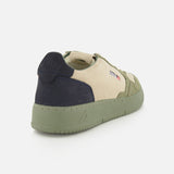 The AUTRY Medalist Low Man Suede Sneaker is a low-top shoe in beige and olive green multicolored suede, accented with a dark navy heel, green platform sole, and subtle side logo details. It’s presented from a rear-angled view against a white background.