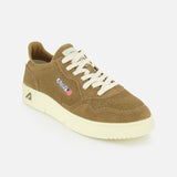 The AUTRY Medalist Low Suede Sneaker is a brown suede shoe inspired by 1980s tennis styles, featuring white laces, a thick off-white sole, and subtle embroidered flag and text details on the side, shown against a plain white background.
