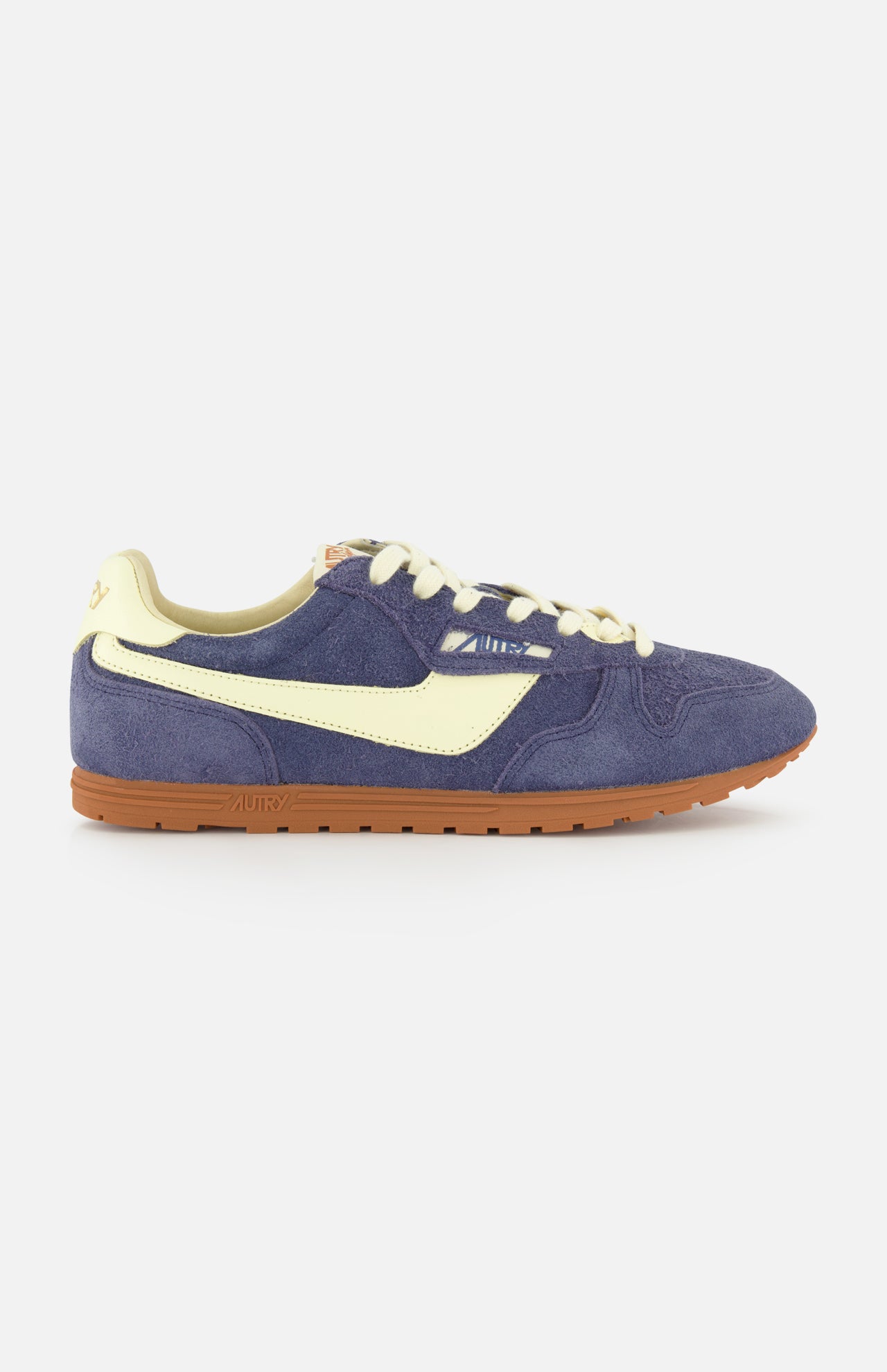 Side view of the AUTRY Windspin Low Suede Sneaker, showcasing a blue suede upper with cream accents and laces, plus a brown rubber sole, all set against a plain white background.