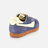 The AUTRY Windspin Low Suede Sneaker features blue suede, cream accents, a brown rubber sole, and gold AUTRY branding on the heel, shown from the back angle.