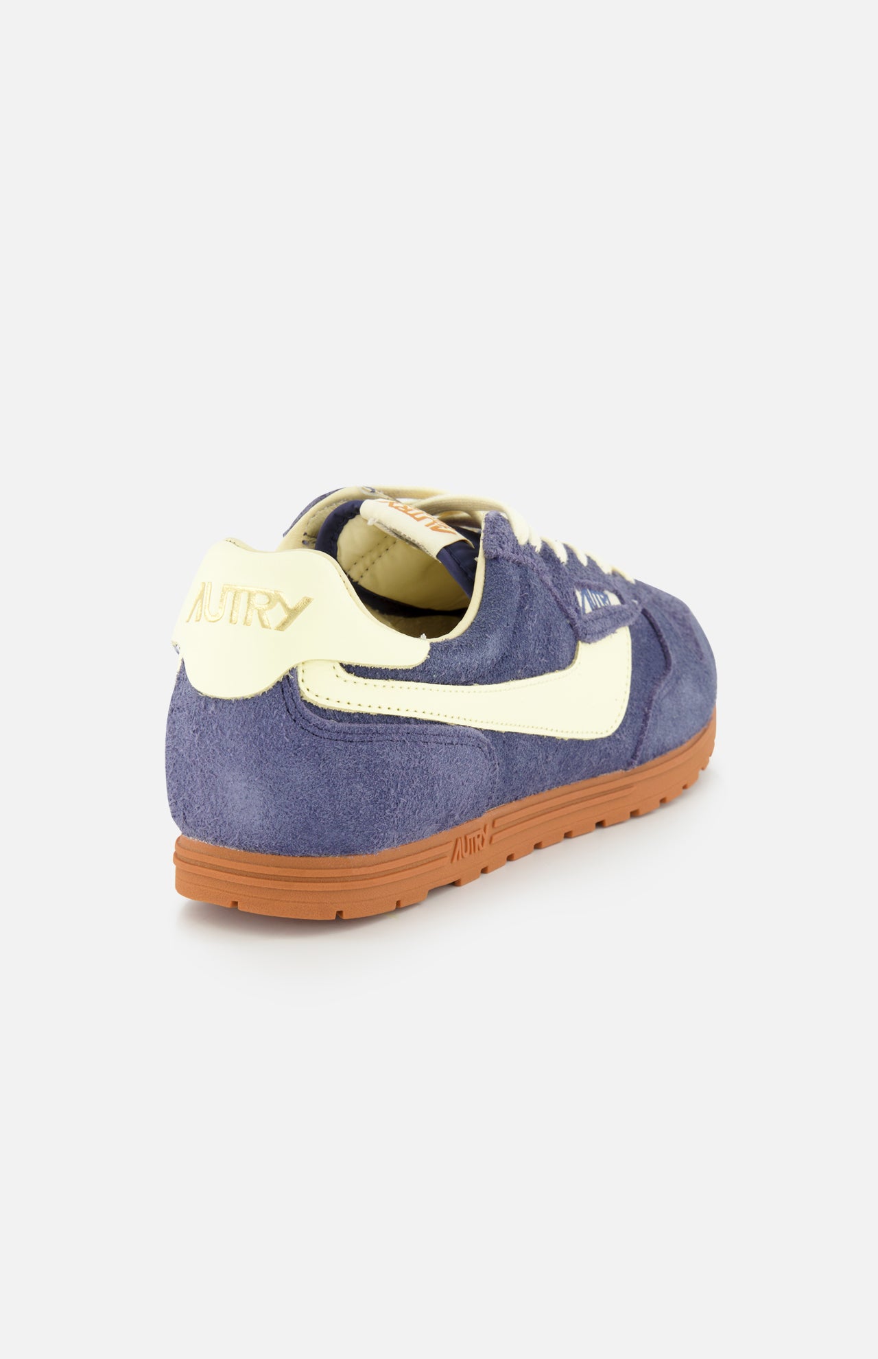 The AUTRY Windspin Low Suede Sneaker features blue suede, cream accents, a brown rubber sole, and gold AUTRY branding on the heel, shown from the back angle.